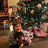 Bobby a rejoint le concours — aidez-le/la à gagner de superbes lots ! boy, dog, christmas_tree, holiday, decorations, lights, presents, festive, smiling, indoor, child, pet, sweater, floor, home, celebration, happy, crouching, cute, warm