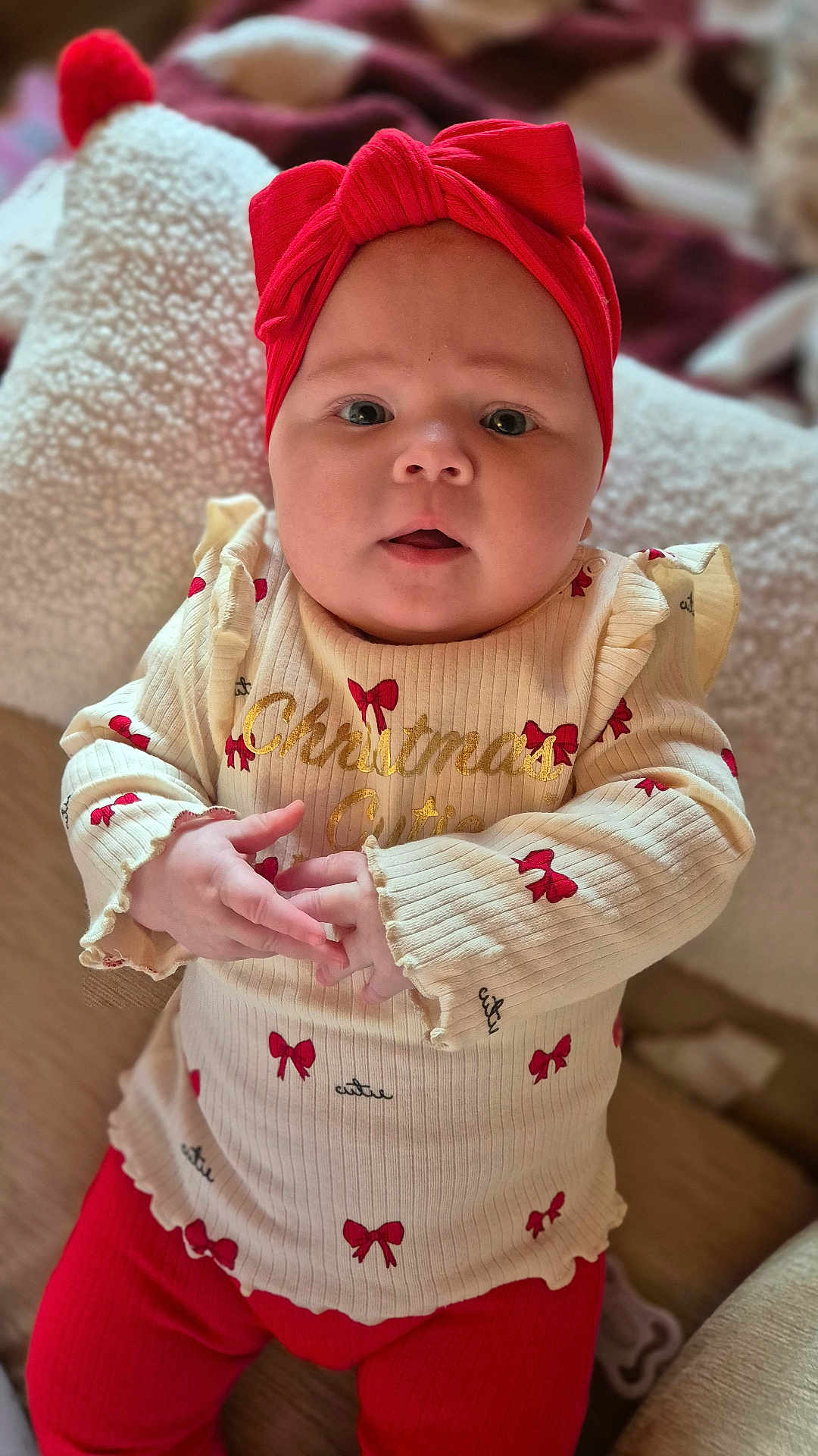 Aleri joined the competition — help win amazing prizes! baby, infant, child, red_headband, cream_sweater, red_bows, cute, portrait, holiday, christmas, indoors, soft_focus, cozy, hands, sitting, clothing, face, expression, cute_outfit, closeup