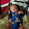 newborn, baby, infant, child, portrait, lying_down, blue_outfit, blanket, bedding, leopard_print, pacifier, pacifier_clip, hospital_bracelet, hands, feet, face, eyes_open, indoors, smartphone, cozy