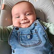 Nolan participe au concours pour gagner de l'argent avec cette photo : baby, infant, denim_overalls, smiling, cute, face, child, seat, cushion, button, clothing, happy, portrait, skin, head, baby_girl, baby_boy, infant_clothing, indoor, relaxed