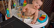 Adam is registered to the contest to win money with this photo: baby, walker, toy, table, plate, clutter, baby_gate, indoor, child, furniture, colorful, room, household_items, person, infant, blur, reaching, plastic, seat, floor
