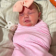 Adaline is registered to the contest to win money with this photo: baby, infant, swaddle, pink, bow, headband, pacifier, sleepy, cute, polka_dot, blanket, bed, resting, newborn, face, human, child, soft, comfort, indoors