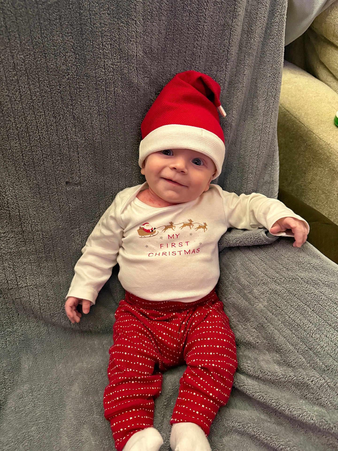 Jaxon joined the competition — help win amazing prizes! baby, infant, christmas, holiday, santa_hat, red_pants, white_shirt, smile, cute, festive, blanket, cozy, indoor, child, person, happy, holiday_clothing, sitting, couch, portrait