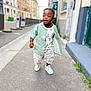 Malick participe au concours pour gagner de l'argent avec cette photo : building, casual_clothing, child, city, curly_hair, cute, daylight, fashion, green_shirt, happy, outdoor, playful, portrait, shorts, sidewalk, sneakers, street, toddler, urban, walking