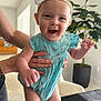 Madison joined the competition — help win amazing prizes! baby, child, smiling, happy, onesie, headband, bow, indoor, person, hands, plant, potted_plant, furniture, table, arm, face, cute, expression, infant, light