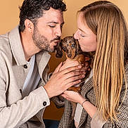 Alpha participe au concours pour gagner de l'argent avec cette photo : man, woman, puppy, dog, dachshund, pet, love, affection, holding, kissing, portrait, indoor, beige_background, casual_clothing, couple, cute, hands, long_hair, curly_hair, jeans