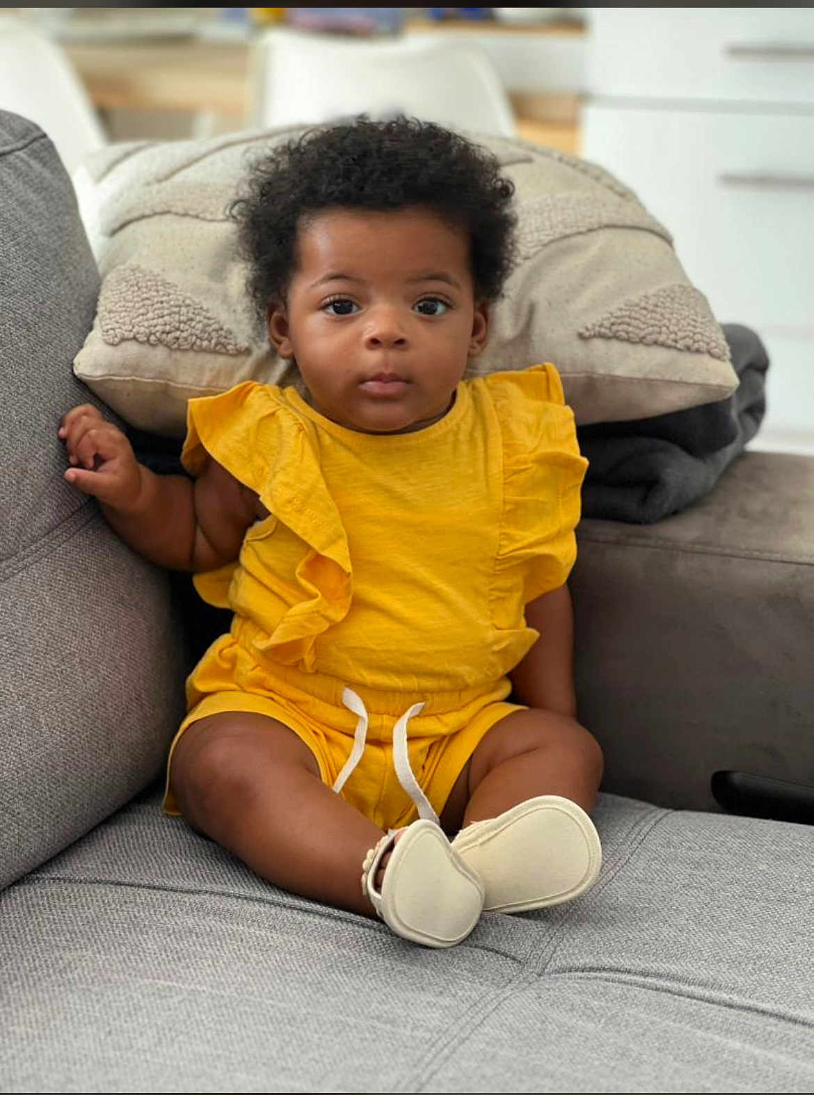 Eden participe au concours pour gagner de l'argent avec cette photo : baby, child, yellow_clothing, sitting, couch, pillow, indoor, curly_hair, footwear, home, cute, portrait, expression, infant, furniture, relaxing, comfort, cozy, person, casual