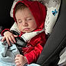 baby, blanket, car_seat, child, clothing, cozy, cute, face, hand, headrest, indoors, infant, pattern, peaceful, red_hoodie, resting, safety_harness, sleeping, toddler, young_child