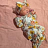 newborn, baby, sleeping, floral_outfit, headband, pink_blanket, soft_texture, infant, peaceful, cute, portrait, child, sleep, wrapped, resting, indoors, cozy, adorable, small_hands, peace