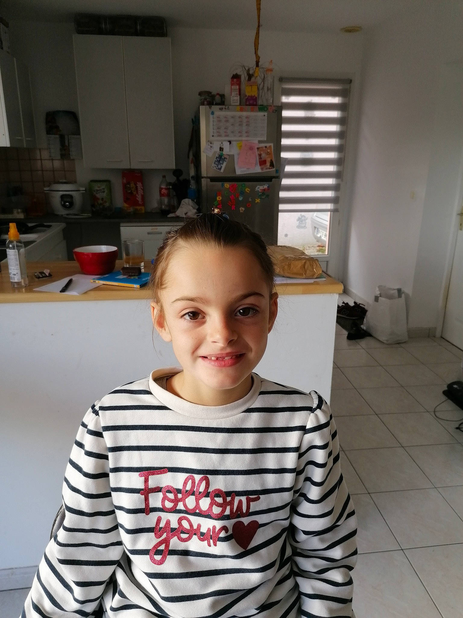 Soraya participe au concours pour gagner de l'argent avec cette photo : cheek, child, chin, eye, flooring, forehead, fun, happy, joy, kitchen, long_sleeved_t_shirt, person, refrigerator, room, sitting, sleeve, smile, standing, t_shirt, toddler