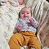 baby, smiling, blanket, floral_clothing, mustard_pants, white_socks, bunny_pattern, infant, cute, cozy, soft_texture, indoors, cute_baby, child, portrait, happy, lying_down, clothing, newborn, person