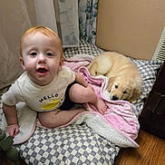 Henry joined the competition — help win amazing prizes! child, toddler, baby, puppy, dog, blanket, cushion, floor, indoor, wood_floor, curtain, shirt, smiling, sitting, pet, cute, cozy, home, animal, young