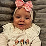 baby, child, smiling, pink_bow, headband, minnie_mouse, white_clothing, lace_collar, closeup, portrait, indoor, soft_texture, plush_background, cute, happy, infant, person, apparel, face, young
