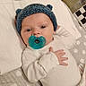 baby, infant, pacifier, hat, knitted_hat, blue_hat, blanket, white_clothing, lying_down, hand, face, head, cute, soft_texture, indoors, newborn, sleepwear, resting, child, person