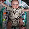 baby, onesie, baby_seat, horse_prints, arms_stretched, infant, cute, child, indoor, colorful, fabric, pattern, comfort, seat, expression, face, legs, foot, padded, playful