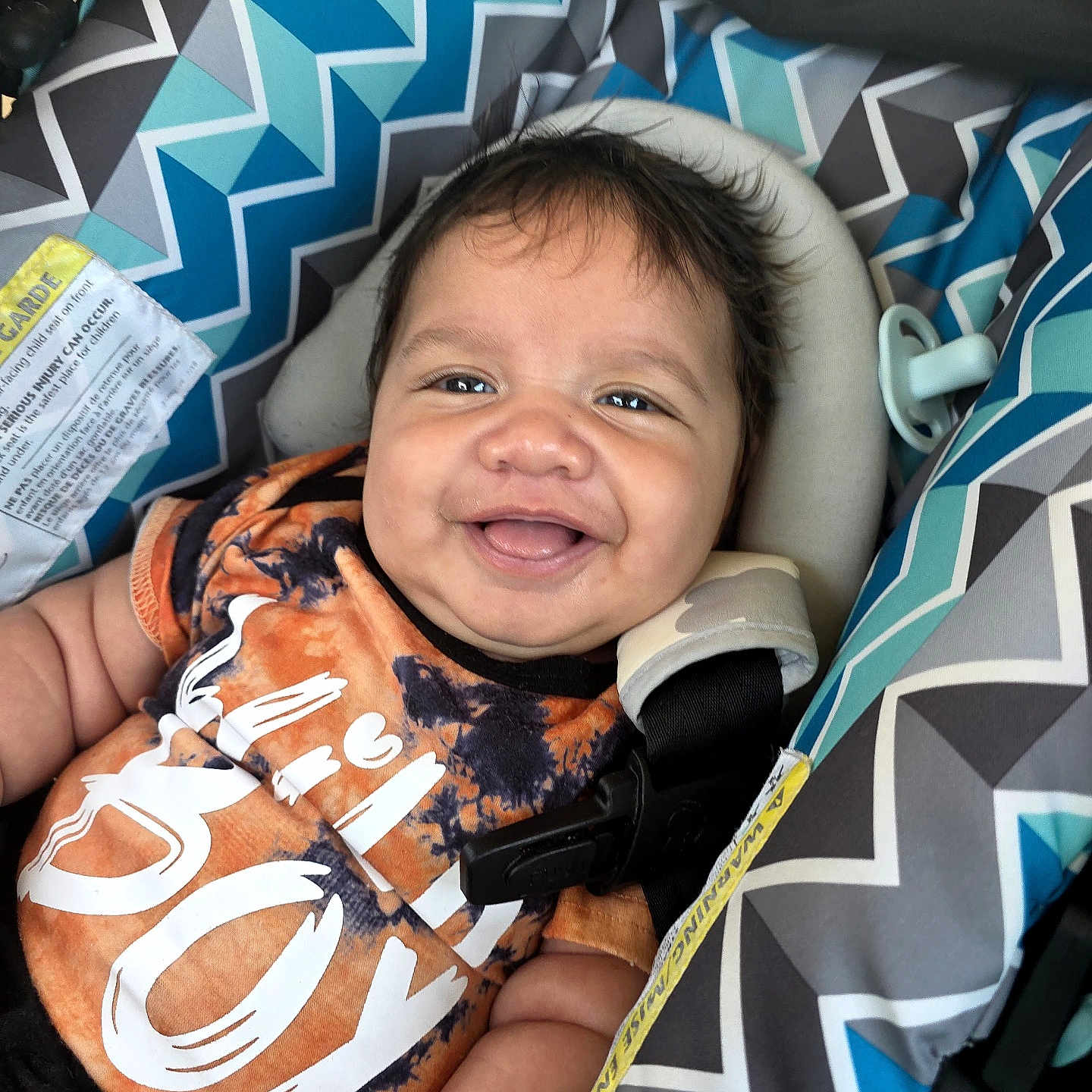Azaryee joined the competition — help win amazing prizes! baby, black_shirt, car_seat, child, closeup, clothing, comfort, cute, face, happy, head, indoors, infant, orange_shirt, patterned_fabric, person, portrait, seat_belt, smiling, young_child