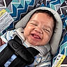 baby, blue, car_seat, child, closeup, clothing, cute, face, geometric_pattern, happy, headrest, indoors, infant, joyful, pattern, person, safety, seatbelt, smiling, straps
