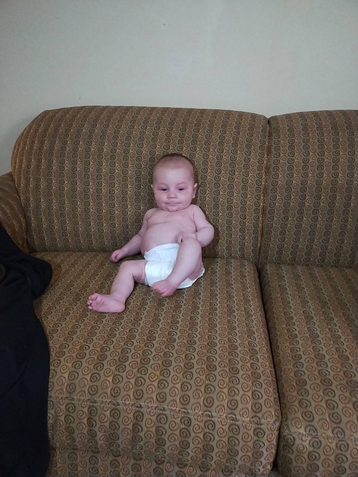 Austin is registered to the contest to win money with this photo: baby, baby_toddler_clothing, comfort, couch, eye, face, floor, flooring, furniture, hardwood, head, knee, linens, living_room, person, sitting, studio_couch, textile, thigh, toddler