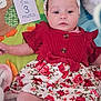 baby, infant, child, red_dress, headband, blanket, plush_toy, soft_toy, card, text, floral_pattern, cute, lying_down, indoors, person, skin, face, legs, hand, clothing