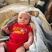 Wyatt joined the competition — help win amazing prizes! baby, baby_boy, blanket, casual, chair, child, clothing, face, footwear, home, indoor, infant, legs, person, portrait, red_onesie, relaxed, sock, soft_texture, window