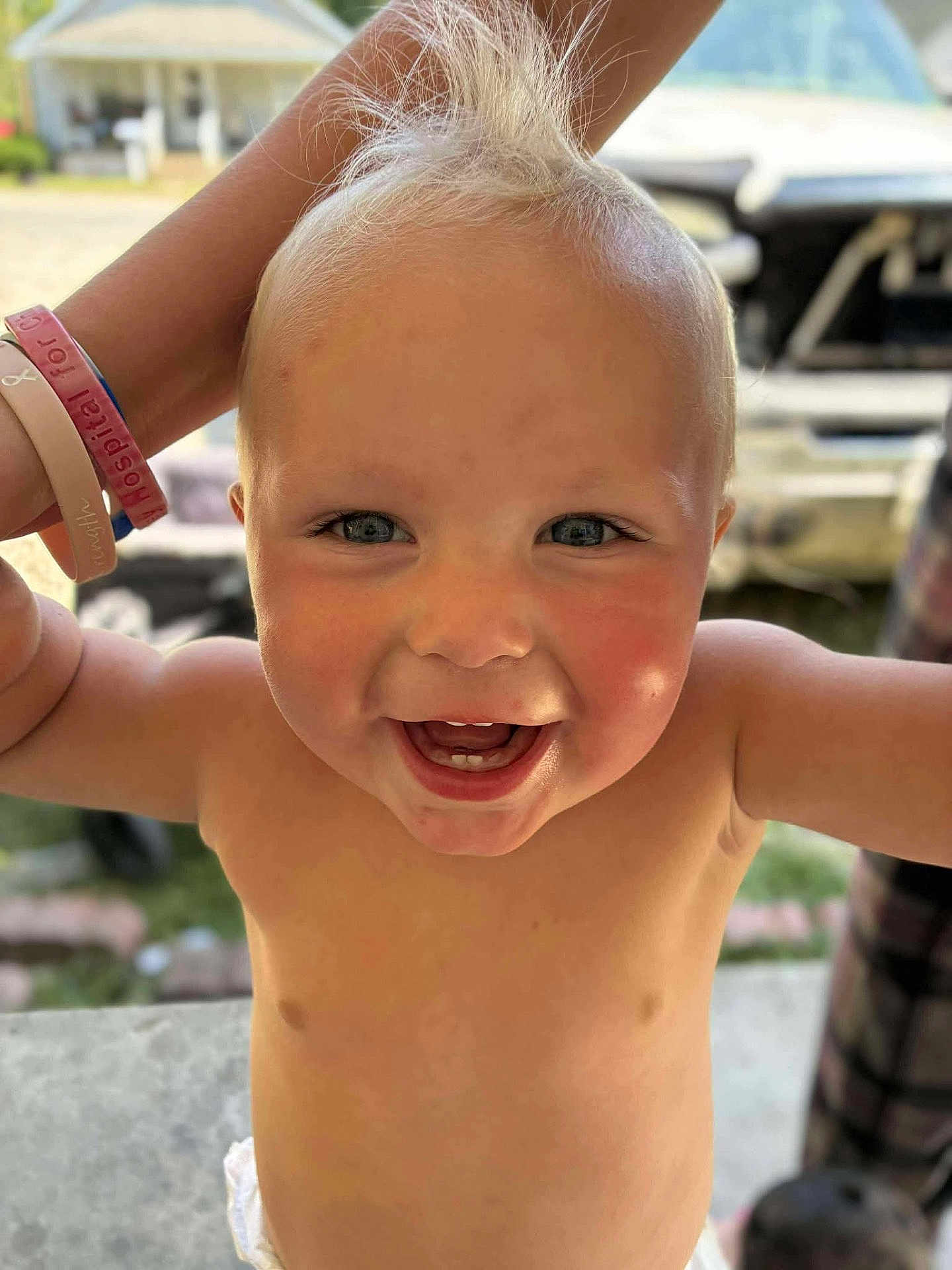 Country is registered to the contest to win money with this photo: toddler, child, smiling, happy, bare_chested, blond_hair, blue_eyes, outdoor, person, face, skin, expression, joy, hair, arm, wristbands, diaper, closeup, daylight, background_blur