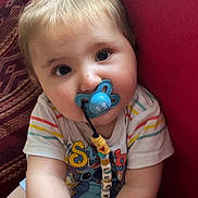 Lucyanno participe au concours pour gagner de l'argent avec cette photo : baby, pacifier, bracelet, striped_shirt, stitch_character, beaded_chain, child, cute, indoor, sitting, red_background, blue_pacifier, smiling, young_child, portrait, colorful_clothing, accessory, light_hair, happy, closeup