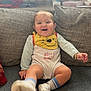 baby, child, smiling, sitting, couch, cushion, onesie, footwear, sock, toy, indoor, happy, face, person, home, plush, casual, clothing, playful, infant
