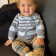 Lucyanno participe au concours pour gagner de l'argent avec cette photo : child, clothing, couch, cozy, cute, face, furniture, happy, home, indoor, person, plaid_pants, portrait, sitting, smiling, striped_sweater, toddler, white_shoes, wooden_cabinet, young_child