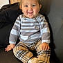 child, clothing, couch, cozy, cute, face, furniture, happy, home, indoor, person, plaid_pants, portrait, sitting, smiling, striped_sweater, toddler, white_shoes, wooden_cabinet, young_child