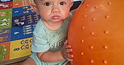 Landon joined the competition — help win amazing prizes! baby, child, orange_ball, play_mat, floor, indoor, toy, curious, sitting, person, wooden_floor, colorful, expression, home, infant, clothing, cute, large_ball, playtime, carpet