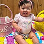 Juliet is registered to the contest to win money with this photo: baby, girl, pink_bow, headband, shirt, easter, colorful_blanket, bunny_pattern, easter_eggs, basket, smiling, tongue_out, wooden_background, sitting, cute, shorts, sparkly_shoes, indoor, happy, celebration