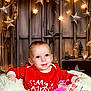 baby, bodypart, candle, clothing, costume, couch, face, finger, furniture, hand, head, indoors, lighting, person, photography, portrait, starsymbol, symbol, t_shirt, text