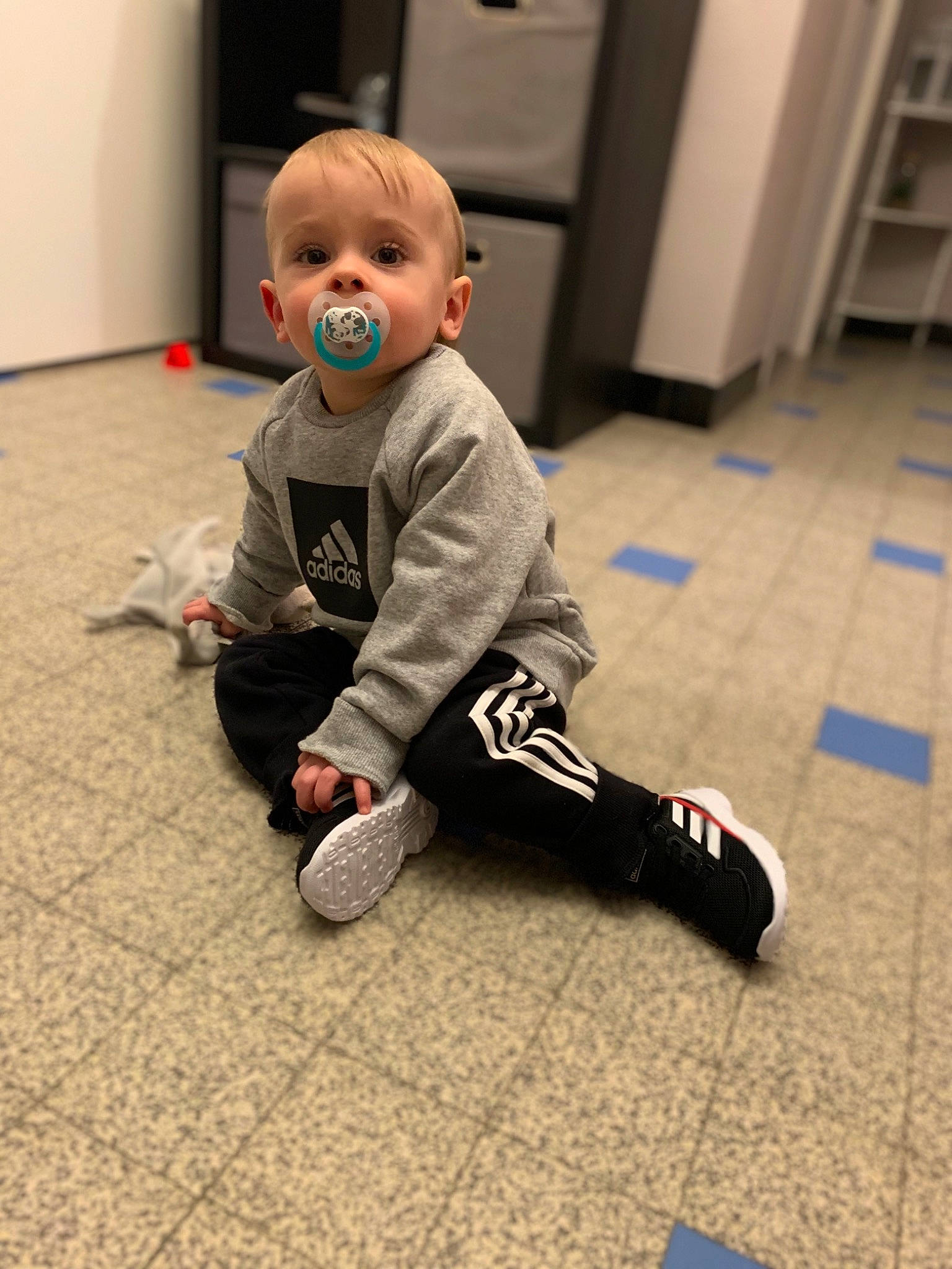 Elio participe au concours pour gagner de l'argent avec cette photo : baby, baby_toddler_clothing, balance, carpet, crawling, floor, flooring, fun, hardwood, human_leg, knee, laminate_flooring, leg, person, sitting, sleeve, sneakers, sock, toddler, wood