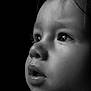 baby, black_and_white, child, close_up, clothing, cute, dark_background, expression, eyelashes, face, hair, head, innocence, monochrome, portrait, profile, skin, soft_lighting, thoughtful, young