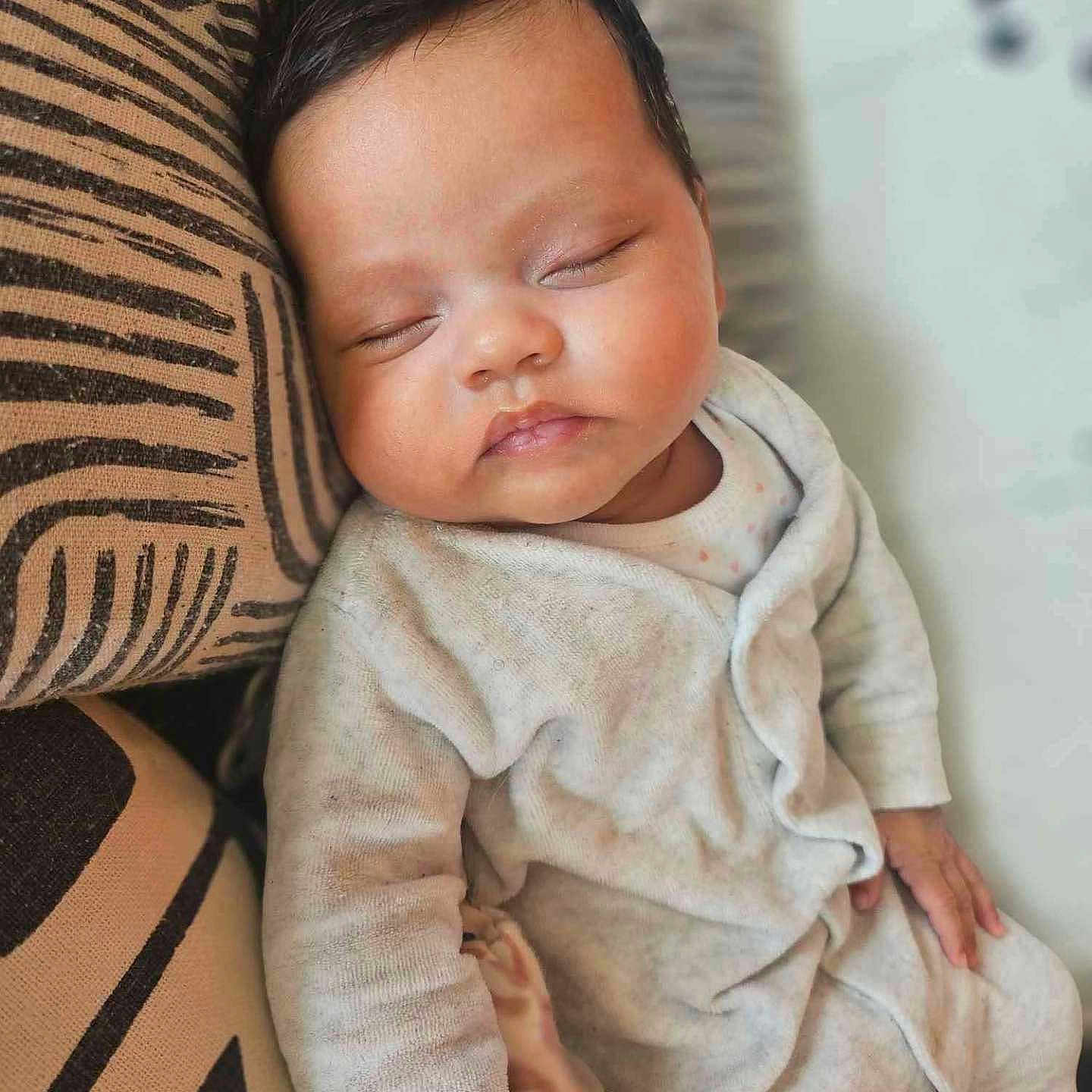 April participe au concours pour gagner de l'argent avec cette photo : baby, child, closed_eyes, comfort, cushion, cute, face, hand, indoors, infant, pajamas, pattern, peaceful, portrait, relaxation, rest, skin, sleeping, soft_lighting, young_child