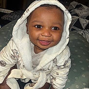 Demonte is registered to the contest to win money with this photo: baby, child, hood, robe, smile, happy, cute, indoor, cushion, pattern, sitting, face, person, skin, apparel, warm, cozy, infant, closeup, portrait