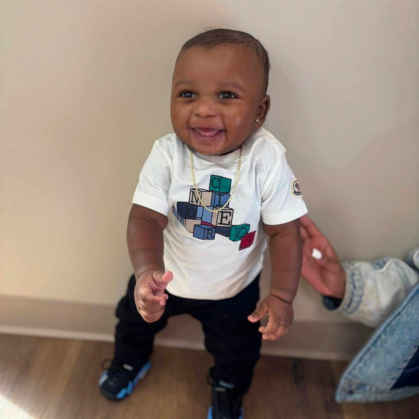 Demonte joined the competition — help win amazing prizes! toddler, child, smiling, indoor, standing, white_tshirt, black_pants, sneakers, drool, hand, adult_support, wooden_floor, beige_wall, happy, portrait, person, cute, young_child, casual_clothing, jewelry