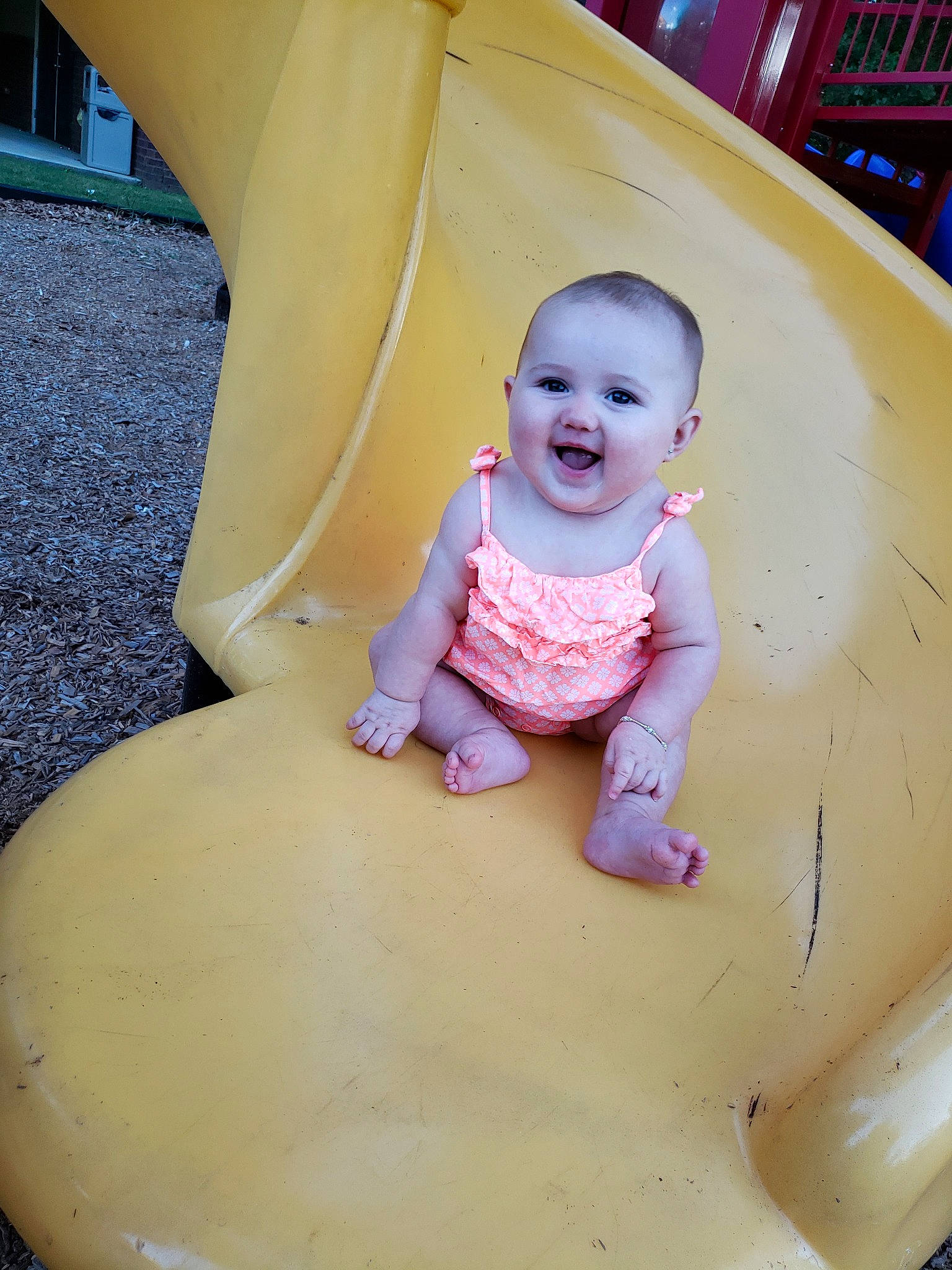 Karley is registered to the contest to win money with this photo: baby, child, fun, leisure, outdoor_play_equipment, person, pink, play, playground, playground_slide, public_space, recreation, sitting, skin, smile, toddler, yellow