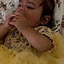 animal_print, baby, blanket, child, cute, dark_hair, expressive, face, hand, indoors, infant, lying_down, pattern, portrait, resting, small_hands, soft_lighting, tulle_skirt, yellow_dress, young_child