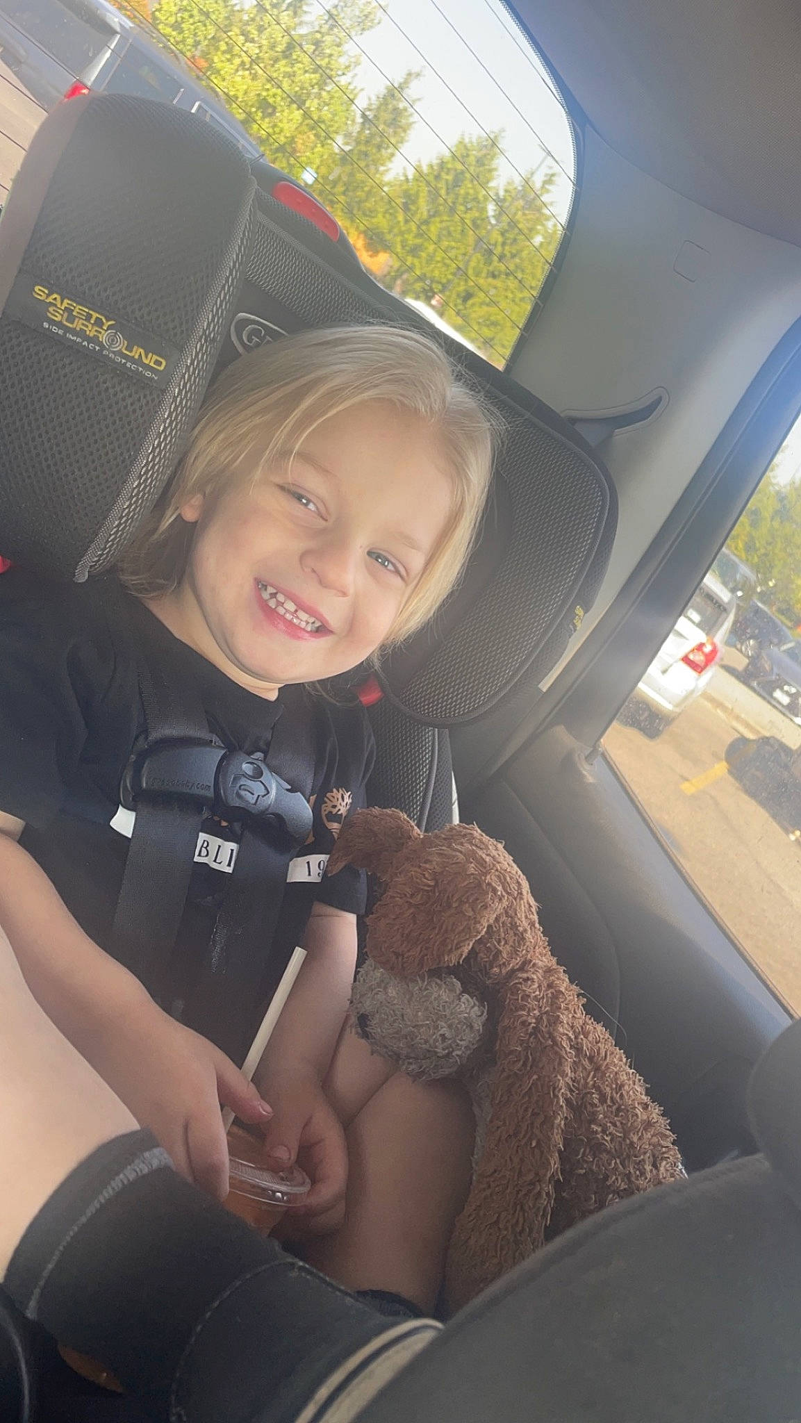 Paxton is registered to the contest to win money with this photo: auto_part, automotive_design, automotive_exterior, baseball_cap, cap, car_seat, car_seat_cover, child, comfort, cool, family_car, head, head_restraint, joy, motor_vehicle, person, smile, steering_wheel, toddler, tree