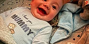 Alfie is registered to the contest to win money with this photo: baby, bed, blanket, child, clothing, comfort, cozy, cute, face, happy, indoors, infant, lying_down, patterned_bedding, pillow, plush, sleepwear, smiling, soft_toy, warm_light