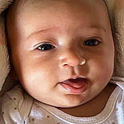 Ariely is registered to the contest to win money with this photo: baby, infant, face, close_up, tongue_out, blanket, onesie, cute, skin, expression, child, newborn, adorable, soft, portrait, young, person, sleepwear, head, cheeks