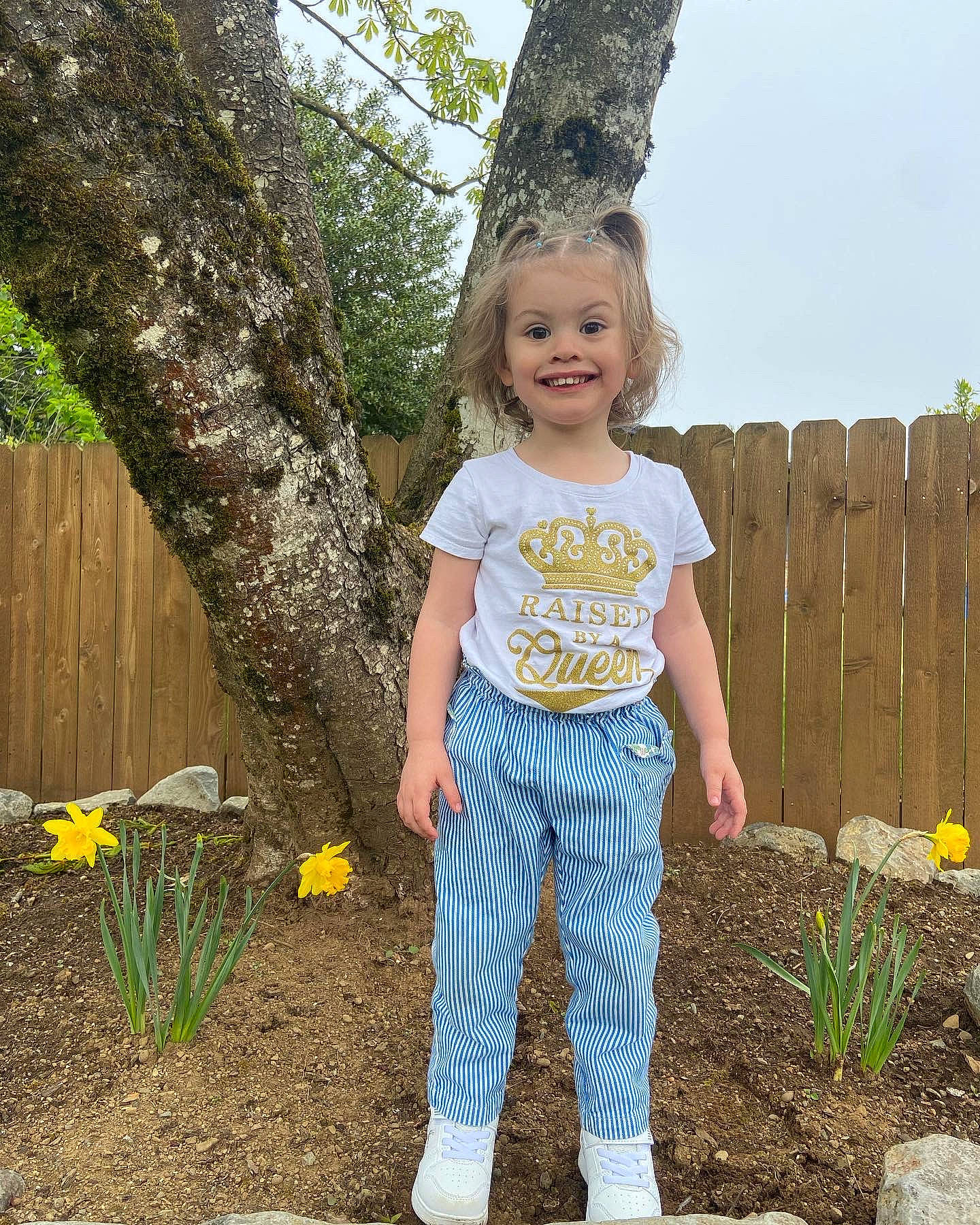 Elizabeth is registered to the contest to win money with this photo: denim, fence, flower, grass, happy, joy, leaf, leg, leisure, people_in_nature, person, plant, sky, smile, standing, summer, t_shirt, tree, trunk, waist