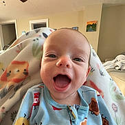 Colton is registered to the contest to win money with this photo: baby, smile, happy, infant, blanket, onesie, clothing, indoor, face, cute, child, young, cozy, living_room, patterned, home, person, portrait, expression, comfort