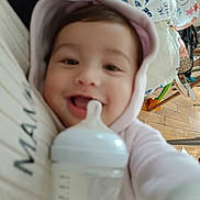 Alhelí participe au concours pour gagner de l'argent avec cette photo : baby, bottle, hoodie, smile, indoor, floor, wooden_floor, baby_gear, person, face, child, clothing, toy, feeding, happy, cute, infant, closeup, hand, warm