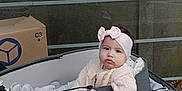 Alhelí participe au concours pour gagner de l'argent avec cette photo : baby, child, stroller, headband, pink_bow, knitted_sweater, outdoor, cardboard_box, bus_stop, signage, gray_stroller, person, infant, cute, seated, urban, sidewalk, casual_clothing, young_child, portrait