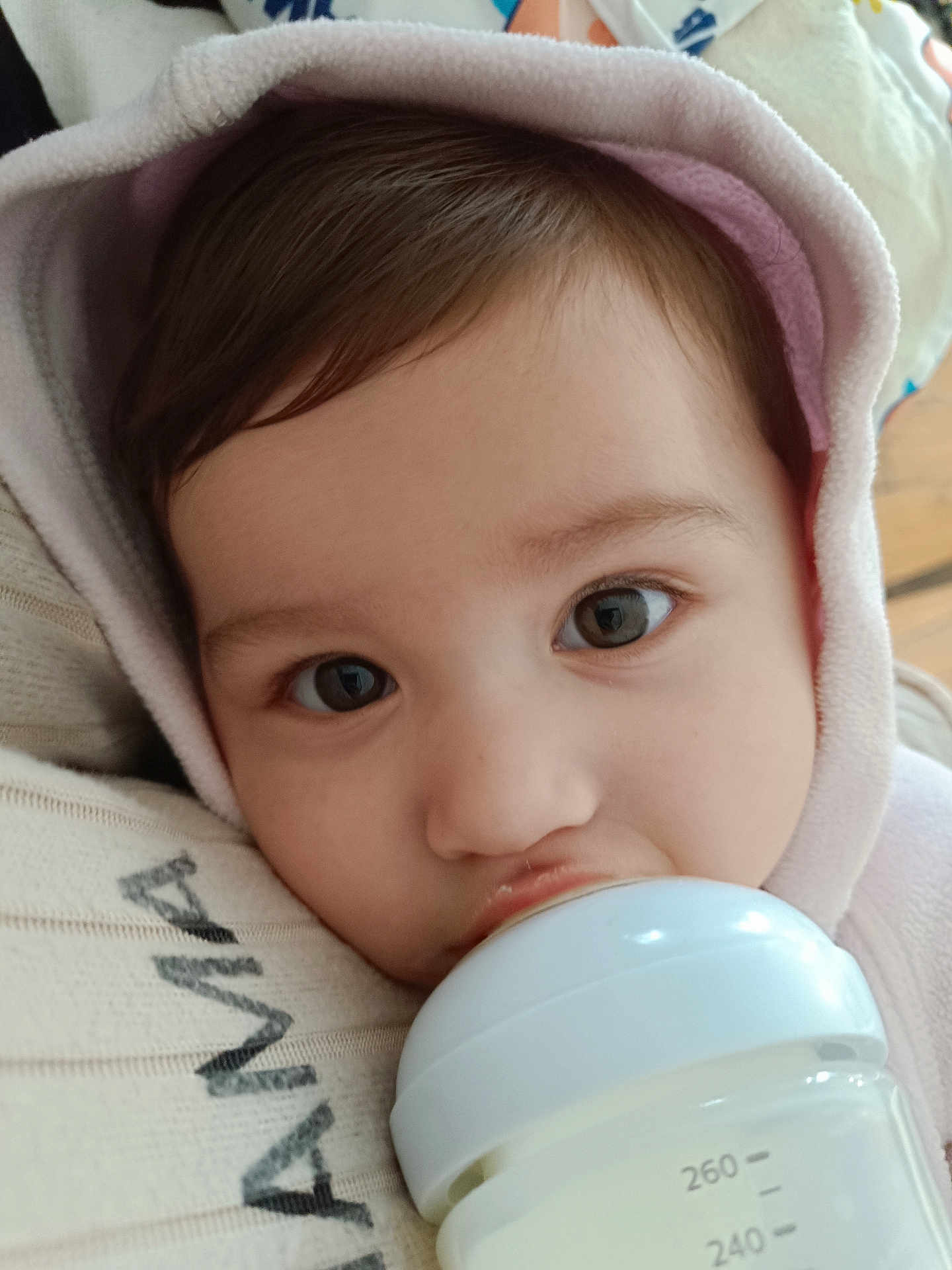 Alhelí participe au concours pour gagner de l'argent avec cette photo : baby, bottle, milk, infant, close_up, face, hood, blanket, feeding, cute, child, soft, skin, eyes, portrait, indoors, warm, comfort, young, person