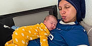 Emmy a rejoint le concours — aidez-le/la à gagner de superbes lots ! baby, woman, sleeping, yellow_onesie, blue_shirt, towel, face, indoor, cozy, cute, child, person, resting, pacifier, bed, blanket, relaxing, skin, headwear, portrait