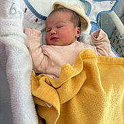 Emmy a rejoint le concours — aidez-le/la à gagner de superbes lots ! newborn, baby, sleeping, blanket, hat, infant, cozy, soft, pink_clothing, yellow_blanket, baby_carrier, peaceful, resting, face, head, person, child, indoors, comfort, cushion