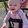 Poppy is registered to the contest to win money with this photo: baby, child, swing, playground, smiling, striped_clothing, outdoor, sunlight, person, happy, infant, hand, feet, adult, fence, trees, chain, play_equipment, casual_clothing, joy
